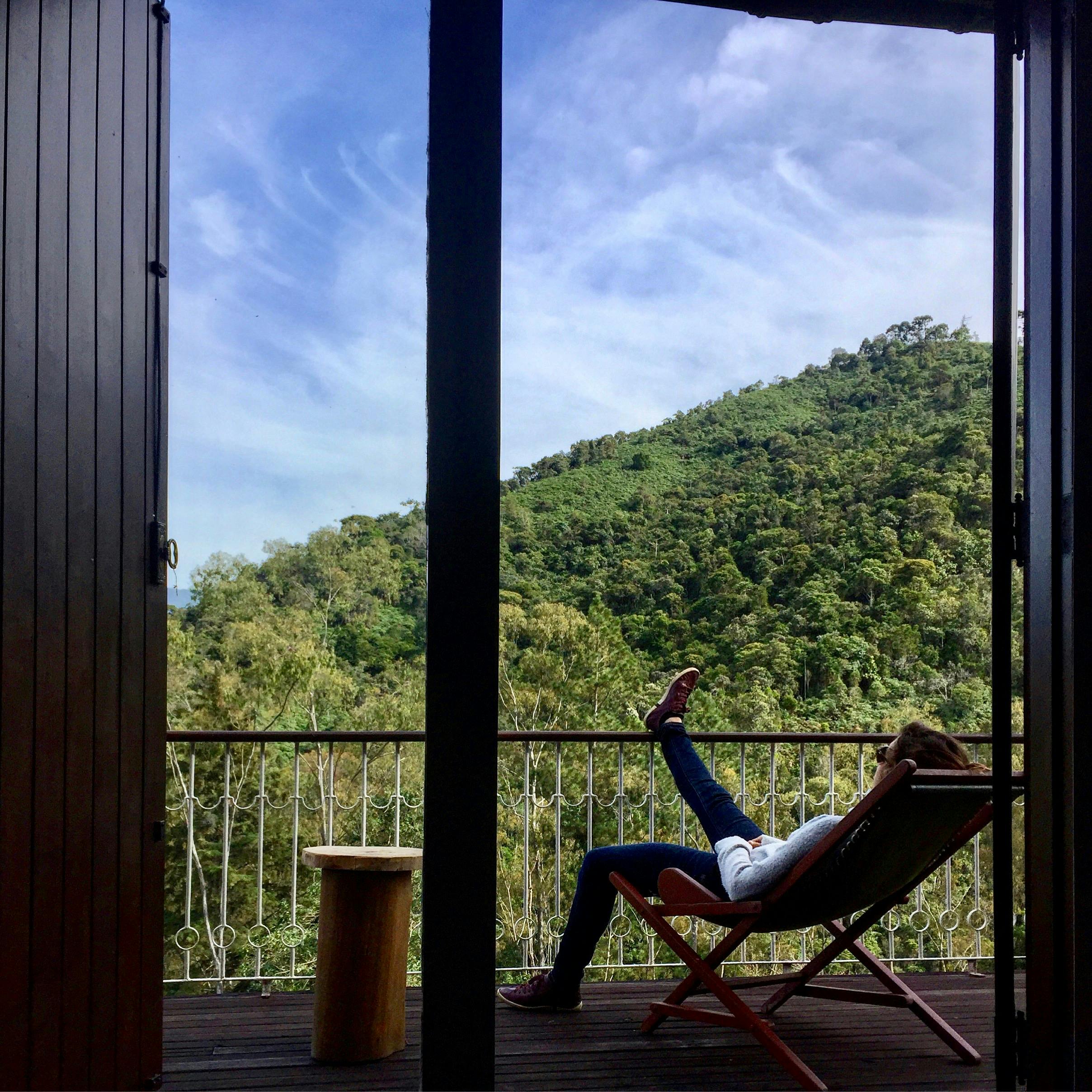 MJESTO ZA MENE Woman enjoying a serene moment on a balcony overlooking lush Brazilian mountains.